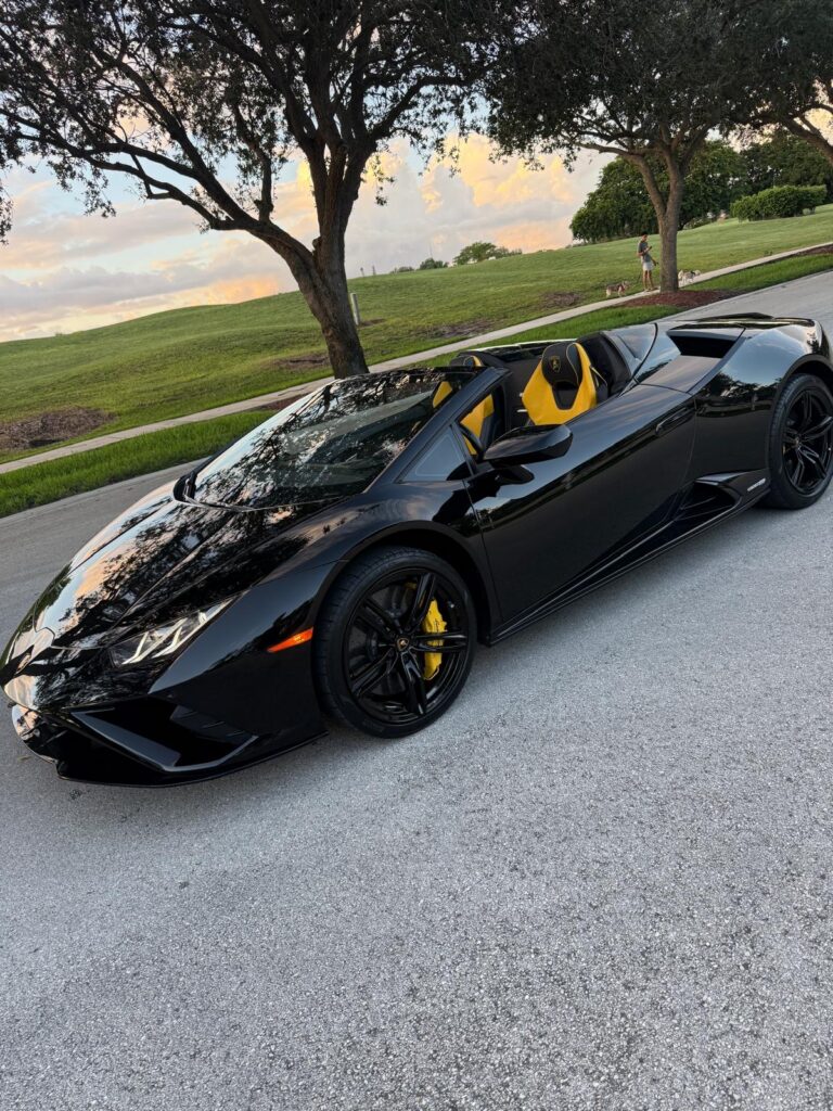 Black Lamborghini Huracán EVO Spyder with the roof down and yellow seats